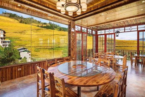 a dining room with tables and chairs and a large window at Longji Forest Lodge in Heping