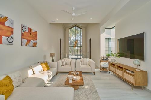 a living room with white furniture and a flat screen tv at SaffronStays Hermes Cove in Kīhīm