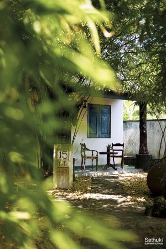 a bench in front of a white building with a window at Sethuki Elephant Cottage in Kaduwela