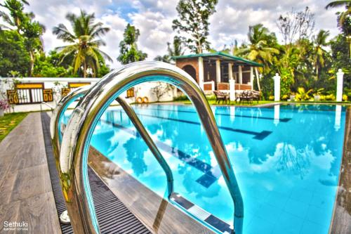 a swimming pool with a slide in front of a house at Sethuki Elephant Cottage in Kaduwela