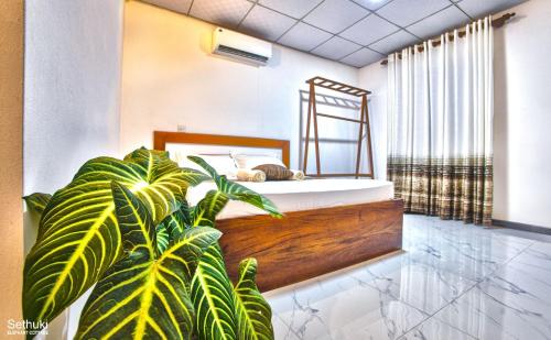 a bedroom with a bed and a plant at Sethuki Elephant Cottage in Kaduwela