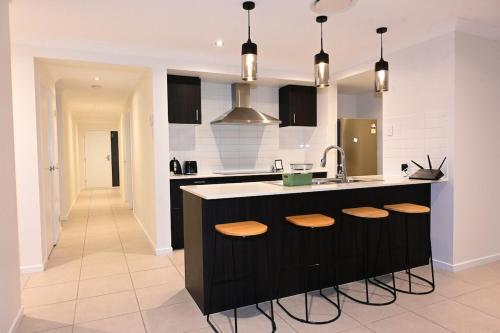 a kitchen with a sink and a counter with stools at New Spacious 4 Bedroom Retreat fully air conditioned in Loganholme in Loganholme