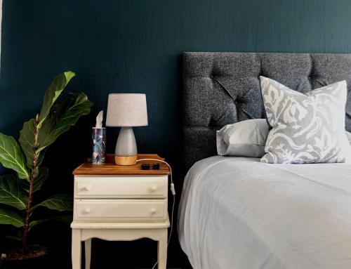 a bedroom with a bed and a nightstand with a lamp at De Nachte Guest Suites in Johannesburg