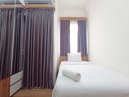 una camera da letto con un letto e una finestra con tende di Comfort and Cozy 2BR Cordova Edupartment Semarang Apartment By Travelio a Semarang