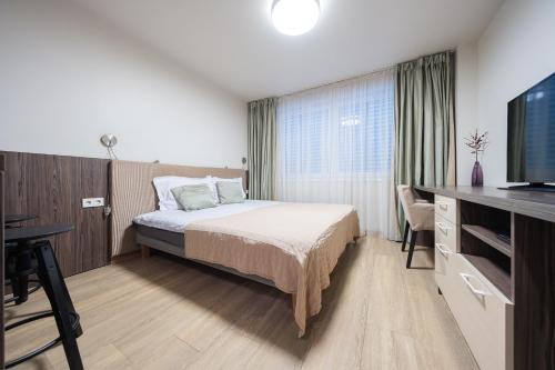 a hotel room with a bed and a flat screen tv at Gynėjų Self Check-in Apartments - Lollo Stay in Vilnius