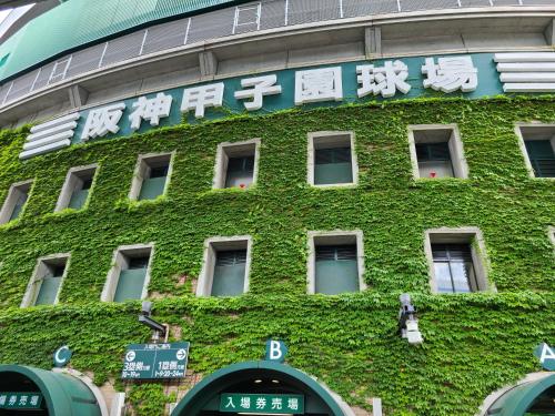 a building covered in green ivy with writing on it at Hotel Public Jam in Osaka