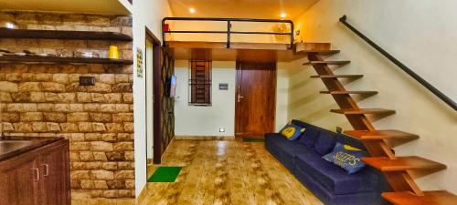 a living room with a blue couch and a staircase at Butterfly home stay in Yercaud