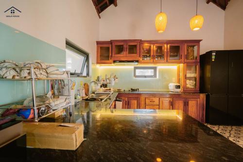 a kitchen with wooden cabinets and a black counter top at Da Dia Seala House in Phú Hạnh (5)
