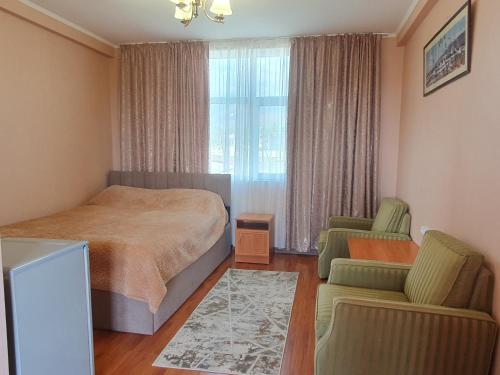 a bedroom with a bed and two chairs and a window at Aquamarine Inn in Cholpon-Ata