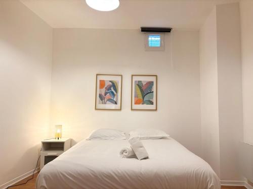 une chambre avec un lit blanc avec deux tableaux au mur dans l'établissement Hypercentre de Roubaix - 4 voyageurs, à Roubaix