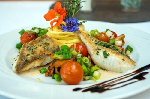 a white plate of food with fish and a salad at Waldhotel Schäferberg in Espenau