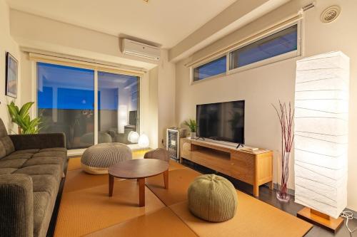 a living room with a couch and a flat screen tv at Cozy Stay Sapporo Maruyama in Sapporo