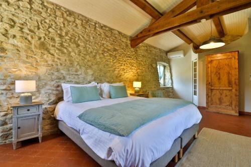 a bedroom with a bed and a stone wall at La Bastide Bleue in Séguret