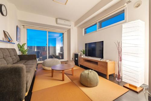 a living room with a couch and a tv at Cozy Stay Sapporo Maruyama in Sapporo