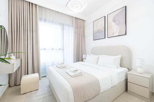 a white bedroom with a large bed and a window at Fresh New 2 Bedroom! Amazing Burj Khalifa View! 5-star Pool & Gym Access! in Dubai