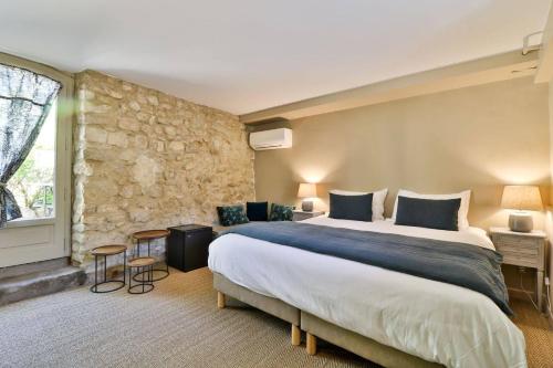 a bedroom with a large bed and a stone wall at La Bastide Bleue in Séguret