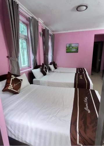 two beds in a room with pink walls at Orient Tam Đảo Hotel in Tam Ðảo