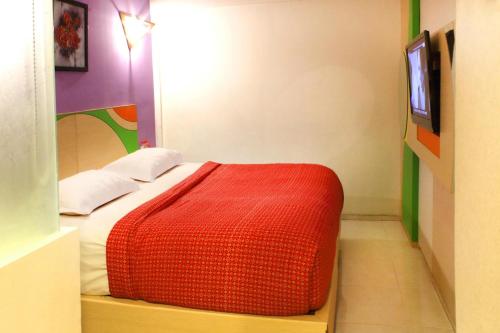 a bedroom with a red bed with a tv on the wall at Hotel Dewarna Sutoyo Malang in Malang