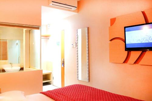 a bedroom with a tv on the wall and a bathroom at Hotel Dewarna Sutoyo Malang in Malang