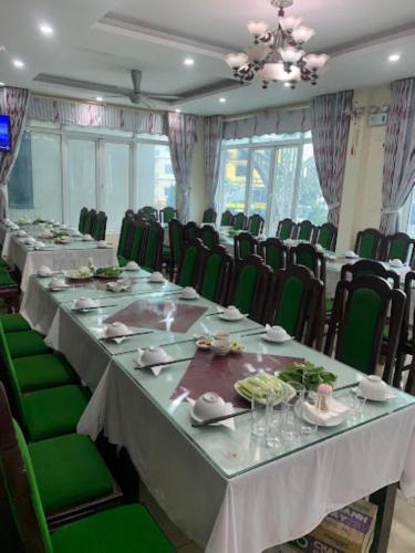 a conference room with long tables and green chairs at Orient Tam Đảo Hotel in Tam Ðảo