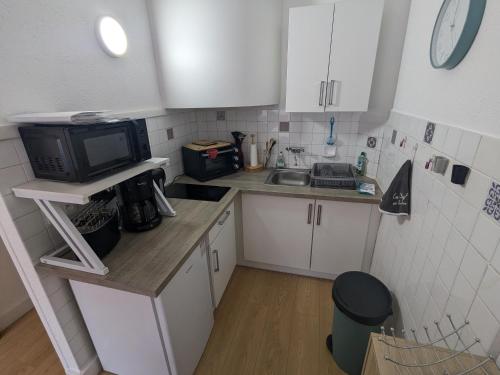 une petite cuisine avec un évier et un micro-ondes dans l'établissement Studio Rue Castellane pour Cure ou Tourisme Vert à 2 min des Thermes, à Amélie-les-Bains-Palalda
