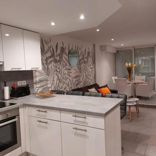 une cuisine avec des armoires blanches et un salon dans l'établissement CAP D'AGDE Naturiste Port Ambonne - POPCORN, au Cap d'Agde