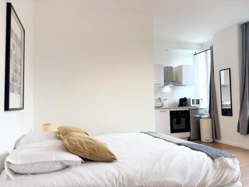 une chambre blanche avec un lit et une cuisine dans l'établissement Grand studio pour 2 voyageurs - Hypercentre, à Roubaix