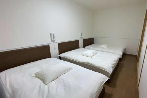 萨摩川内市Nishikata Beach House 1 -西方海岸貸別荘 壱号-的配有白色床单的客房内的两张床