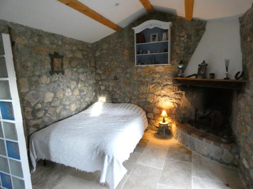 une chambre avec un lit dans un mur de pierre dans l'établissement CABANON PROVENCAL EN PIERRES et ACCES PISCINE LUXE, à Lorgues