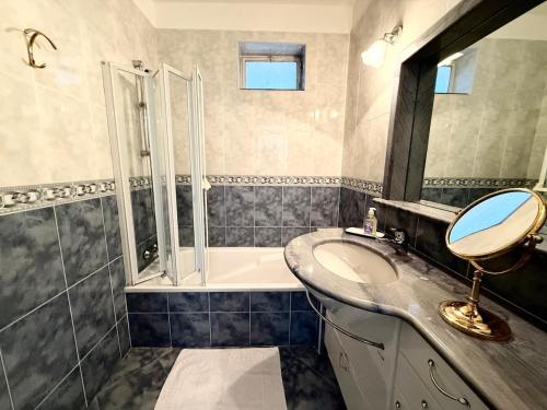 une salle de bain avec un lavabo, une baignoire et un miroir dans l'établissement T3 lumineux terrasse vue mer, à Menton