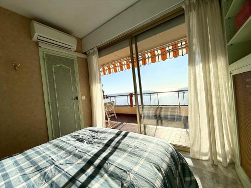 une chambre avec un lit et une grande fenêtre dans l'établissement T3 lumineux terrasse vue mer, à Menton