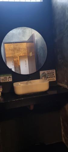 a bathroom sink with a round mirror on a counter at Kugita Bed and Dine in Moalboal