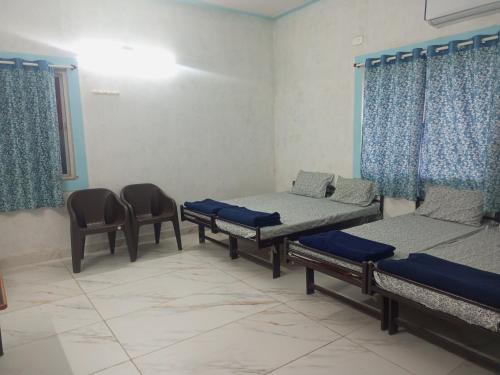 ドワルカにあるDWARKA TOURIST BUNGALOW Only Familyのベッド3台と椅子が備わる部屋