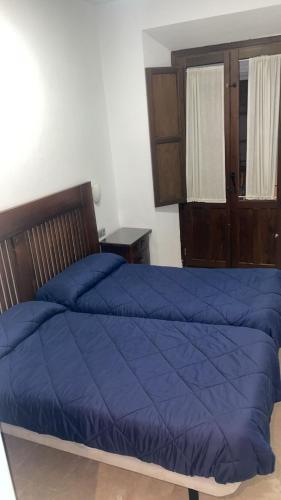 a bedroom with a bed with a blue comforter at Pensión Veracruz 2 in Granada