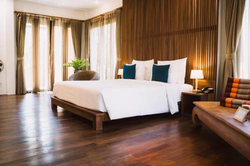 a bedroom with a large white bed with blue pillows at Le Sen Boutique Hotel in Luang Prabang