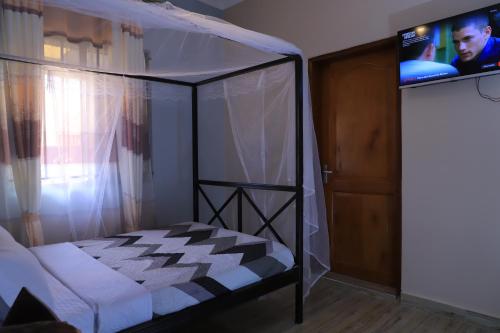 a bedroom with a canopy bed and a television at Duggers Motel Lusaze in Kampala