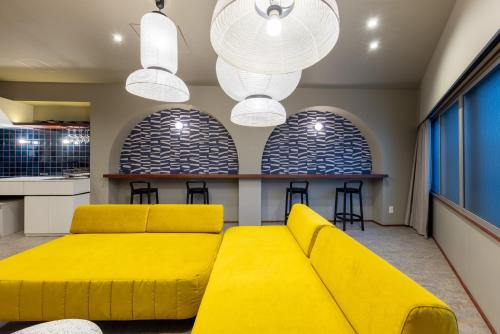 a living room with a yellow couch and stools at ZOPA Horikawa in Kanazawa