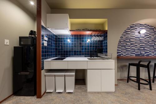 a kitchen with a sink and a blue tiled wall at ZOPA Horikawa in Kanazawa
