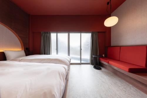 a hotel room with two beds and a red couch at ZOPA Horikawa in Kanazawa