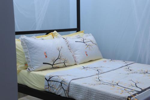 a bed with two pillows with branches on it at Duggers Motel Lusaze in Kampala