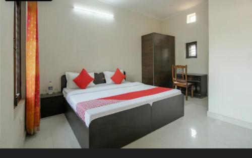 a bedroom with a bed with red pillows and a desk at Maharaja farms in Gurgaon