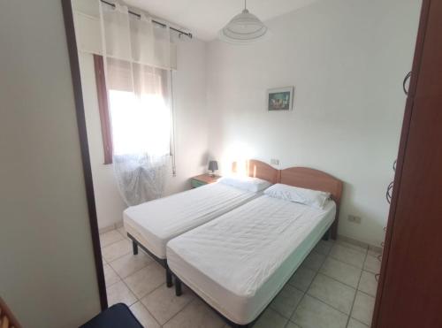 a bedroom with a white bed and a window at Villa Cortina in Rosolina Mare