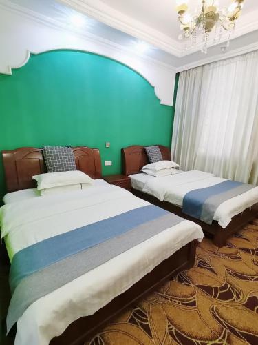 two beds in a room with a green wall at Emeishan Moon Bay Hotel in Emeishan