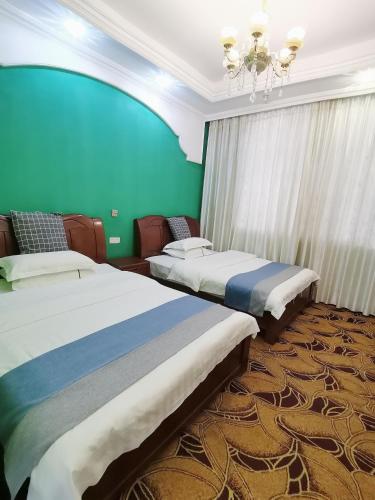 two beds in a room with a green wall at Emeishan Moon Bay Hotel in Emeishan