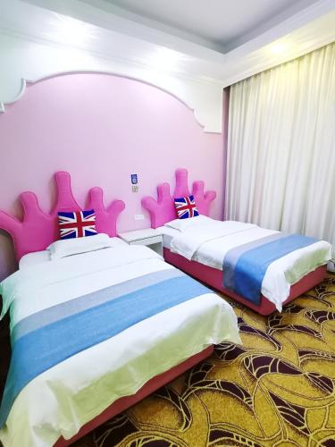 two beds in a room with pink and blue at Emeishan Moon Bay Hotel in Emeishan