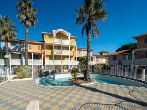 une piscine avec des palmiers devant un immeuble dans l'établissement Belle Creole N08 - 2P4, au Cap d'Agde