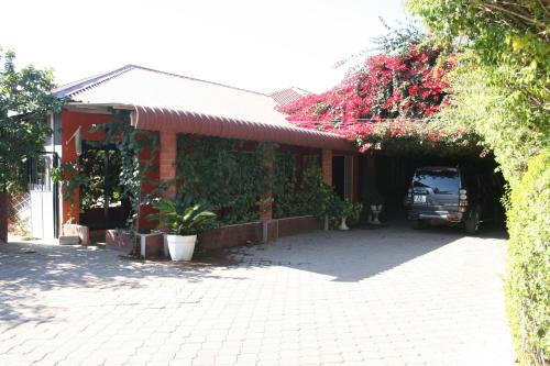 a car is parked outside of a building with flowers at Honeybed Lodge in Lusaka