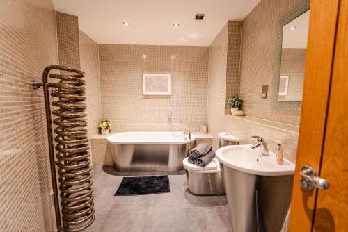 Un baño con bañera, inodoro y lavabo. en Luxurious PENTHOUSE SUITE with Panoramic Views & FREE Parking in Cardiff City Centre, en Cardiff