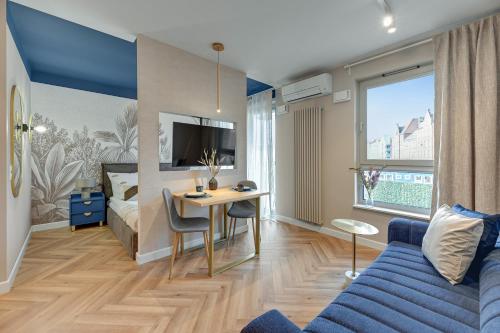 a room with a bed and a table and a blue couch at Żurawie - Food Hall & Stocznia by Downtown Apartments in Gdańsk