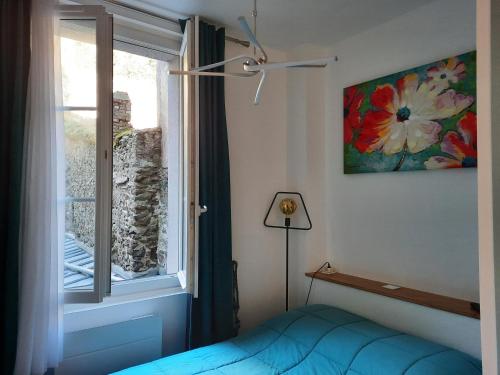 a bedroom with a bed and a window with a painting at LA GRANV'ILLAISE in Granville